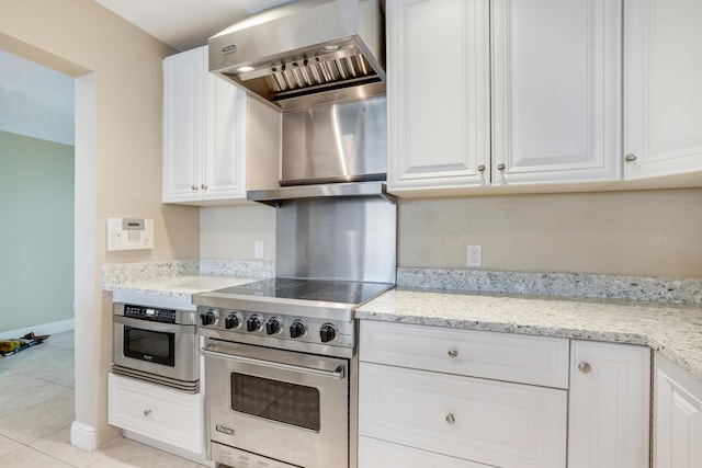 kitchen with light tile patterned floors, light stone counters, premium stove, extractor fan, and white cabinetry