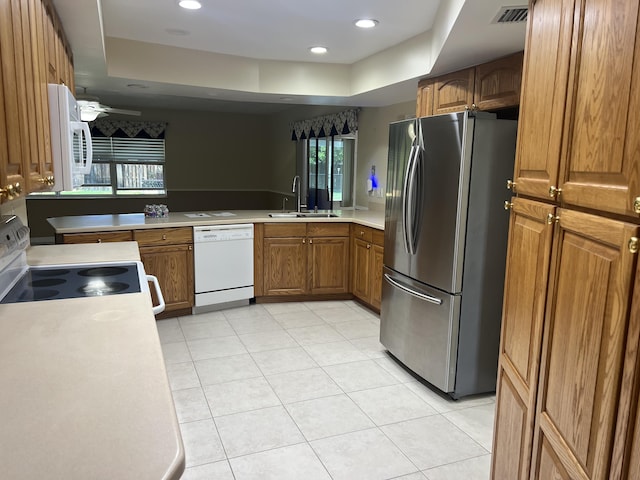 kitchen featuring white appliances, visible vents, a sink, light countertops, and brown cabinets