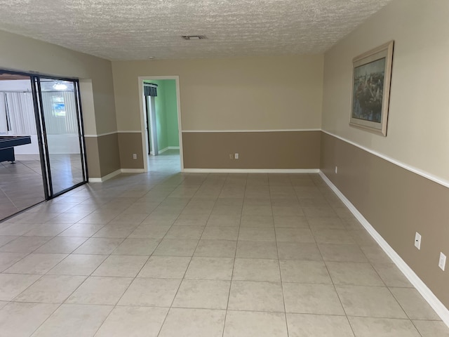 unfurnished room with light tile patterned floors, baseboards, visible vents, and a textured ceiling