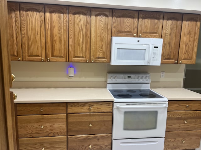 kitchen featuring white appliances and brown cabinetry