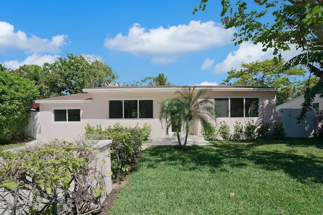 view of front of house featuring stucco siding, a front yard, and fence