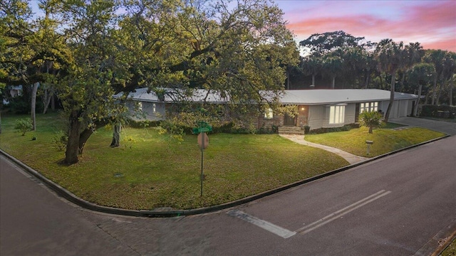 ranch-style house with driveway and a lawn