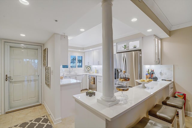 kitchen with a peninsula, white cabinetry, light countertops, appliances with stainless steel finishes, and glass insert cabinets