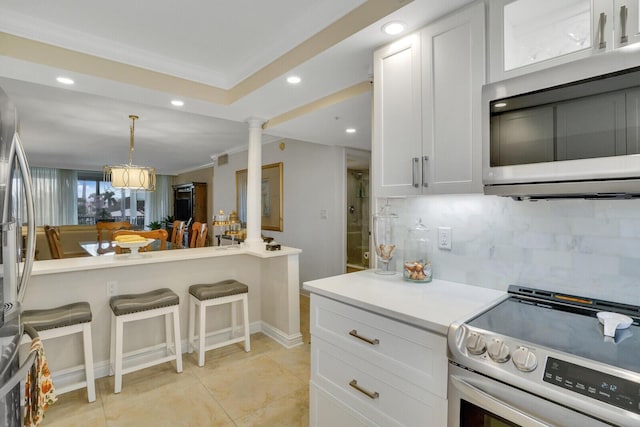 kitchen with light countertops, appliances with stainless steel finishes, white cabinetry, and ornate columns