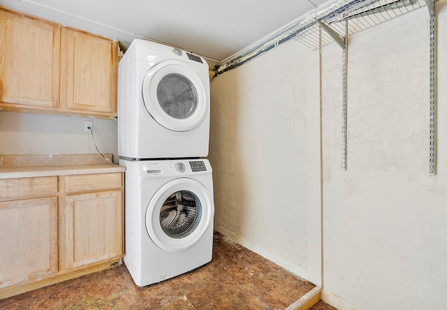 clothes washing area with cabinet space and stacked washer and clothes dryer