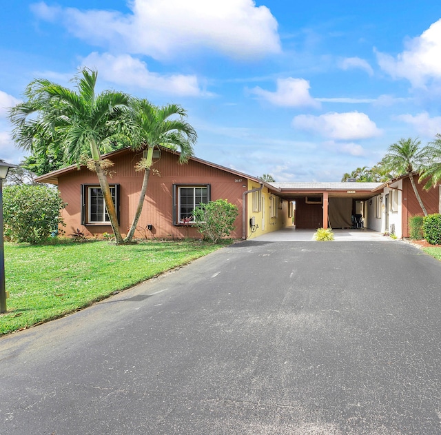 ranch-style home with driveway, an attached carport, and a front yard