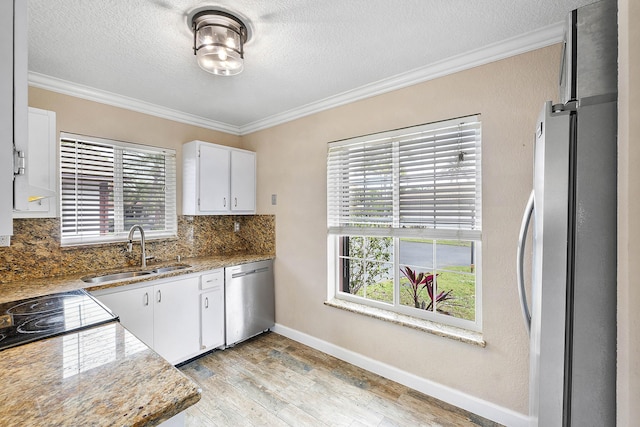 kitchen with a sink, appliances with stainless steel finishes, white cabinets, and dark stone countertops