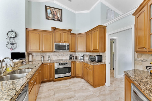 kitchen featuring stone countertops, crown molding, stainless steel appliances, and a sink