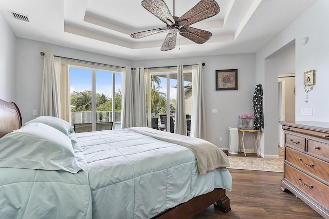 bedroom featuring a raised ceiling, visible vents, dark wood-type flooring, access to outside, and baseboards