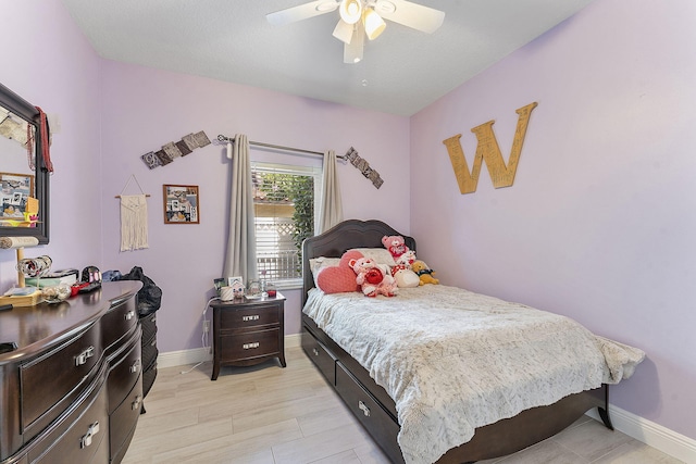 bedroom featuring light wood-type flooring, a ceiling fan, and baseboards