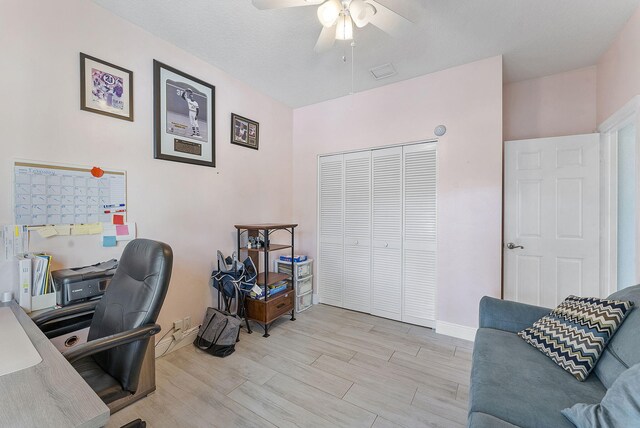 office space with baseboards, light wood-type flooring, visible vents, and a ceiling fan