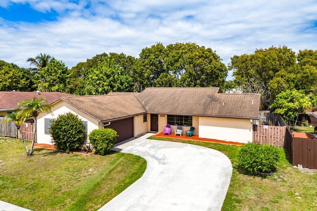 ranch-style house featuring a front yard, fence, driveway, and stucco siding