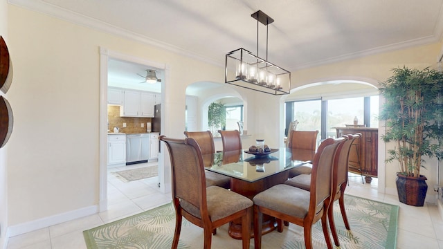 dining area featuring light tile patterned floors, baseboards, arched walkways, and crown molding