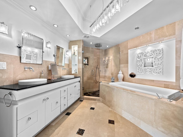 bathroom with a stall shower, ornamental molding, a sink, a garden tub, and tile walls