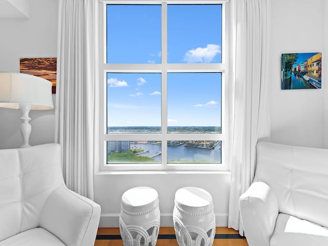 sitting room with a water view, baseboards, and wood finished floors