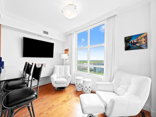 sitting room featuring baseboards, visible vents, crown molding, and wood finished floors