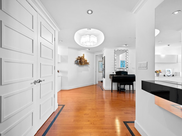 hall with light wood-type flooring, crown molding, baseboards, and recessed lighting