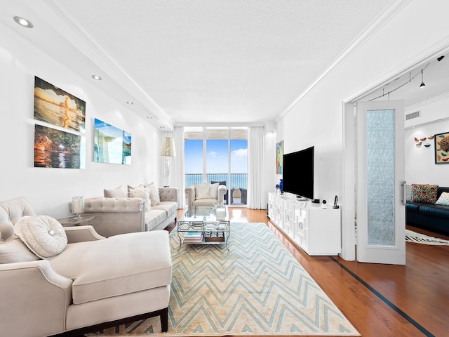 living area featuring visible vents, ornamental molding, wood finished floors, expansive windows, and a textured ceiling