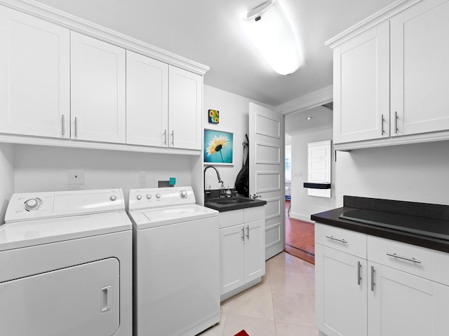 laundry area with cabinet space, light tile patterned floors, washer and clothes dryer, and a sink