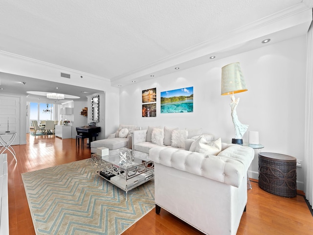 living room with visible vents, ornamental molding, wood finished floors, a textured ceiling, and recessed lighting