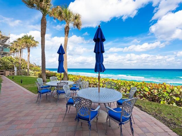 view of patio with outdoor dining space, a water view, and a view of the beach