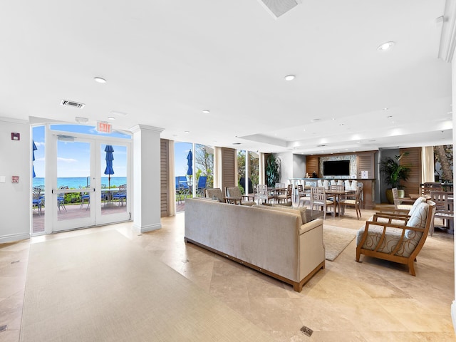 living room featuring recessed lighting, a water view, visible vents, and a healthy amount of sunlight