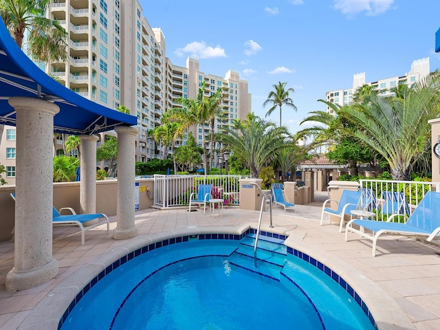 view of swimming pool with a community hot tub, a patio, and a city view