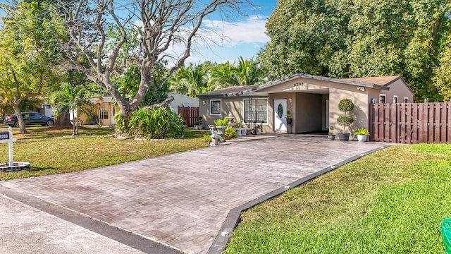 ranch-style home featuring a front lawn, decorative driveway, fence, and stucco siding