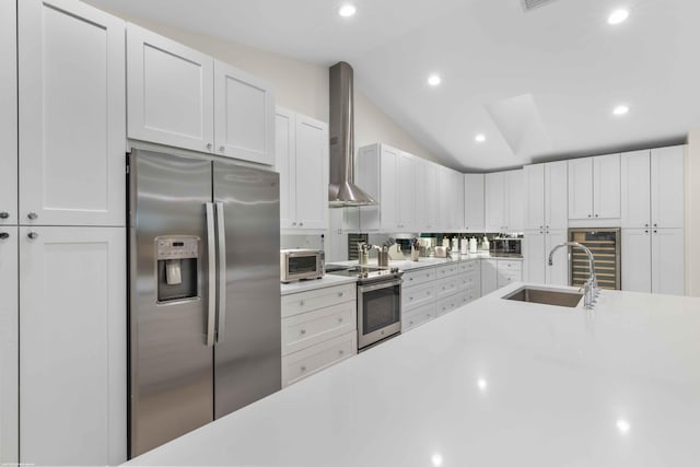 kitchen with appliances with stainless steel finishes, light countertops, vaulted ceiling, and wall chimney range hood