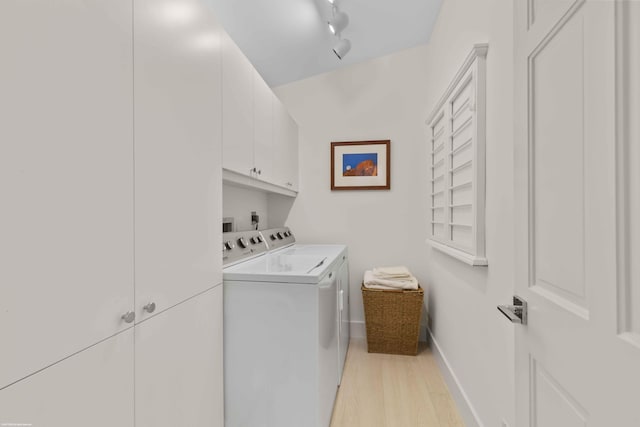 laundry room with baseboards, washer and dryer, light wood-style floors, cabinet space, and rail lighting