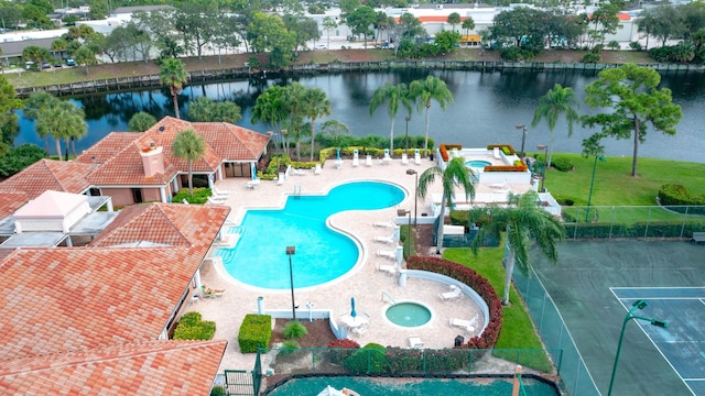 pool with a water view, fence, a lawn, and a patio