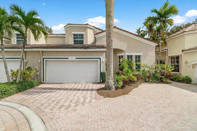 view of front of property featuring an attached garage, a tile roof, decorative driveway, and stucco siding