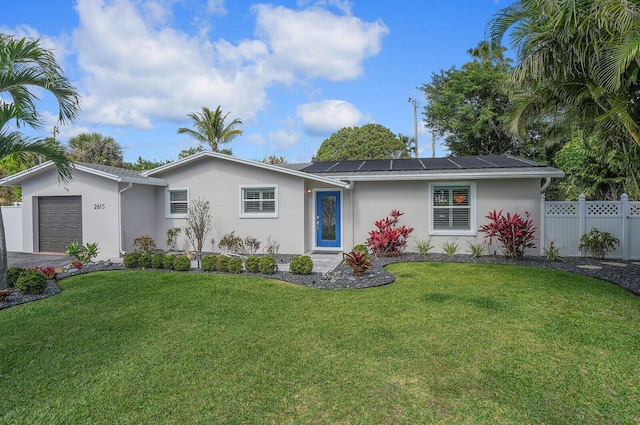 ranch-style house with stucco siding, roof mounted solar panels, fence, a garage, and a front lawn