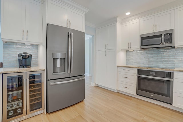 kitchen with beverage cooler, light wood-style flooring, stainless steel appliances, white cabinetry, and backsplash