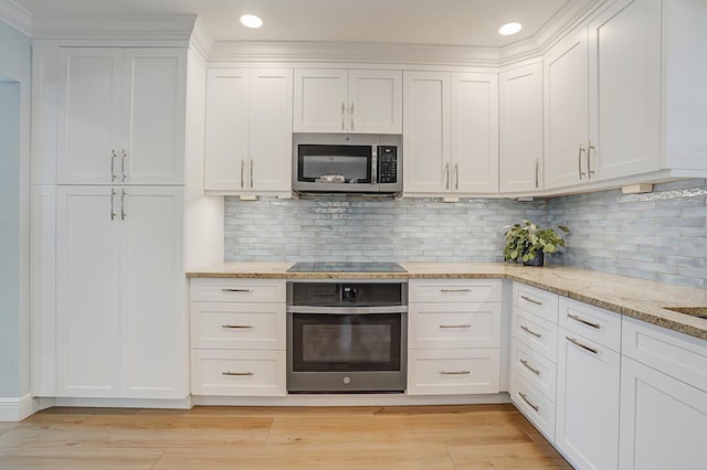 kitchen with light stone counters, stainless steel appliances, light wood-style flooring, decorative backsplash, and white cabinetry