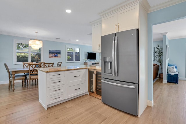 kitchen featuring crown molding, a peninsula, stainless steel refrigerator with ice dispenser, and white cabinets