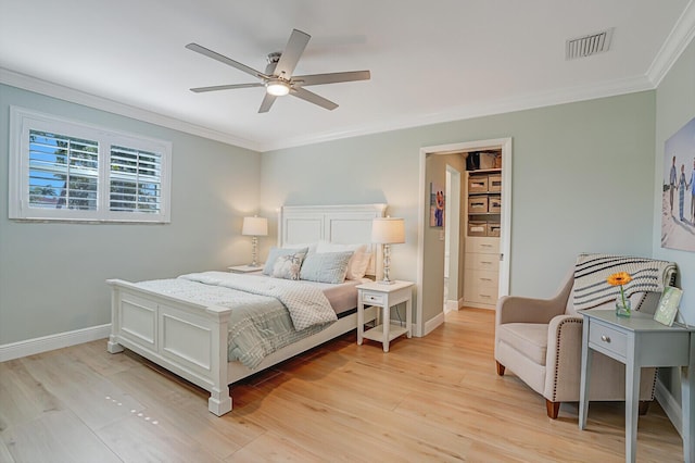 bedroom featuring baseboards, light wood finished floors, visible vents, and crown molding