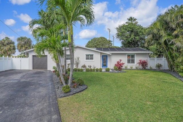 single story home featuring driveway, fence, roof mounted solar panels, a front lawn, and stucco siding