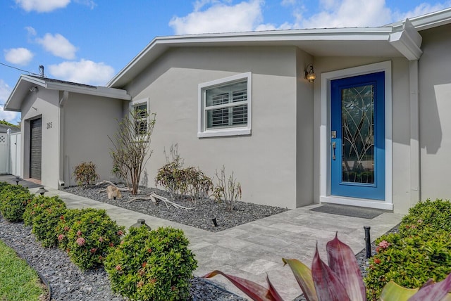 property entrance featuring a garage and stucco siding