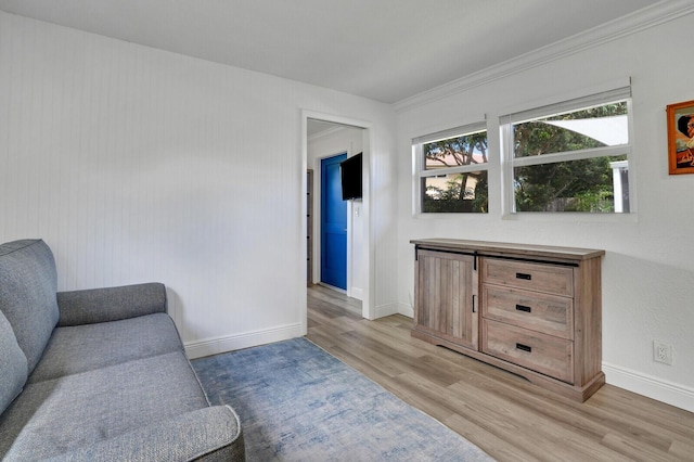 sitting room featuring ornamental molding, light wood finished floors, and baseboards