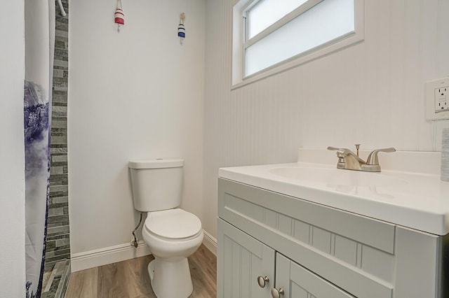 bathroom with baseboards, toilet, wood finished floors, curtained shower, and vanity