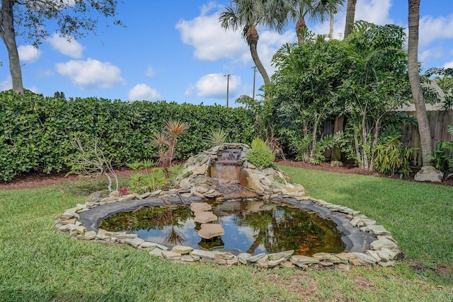 view of yard featuring fence and a garden pond