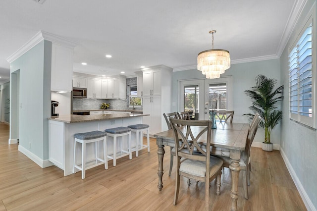 dining space with french doors, ornamental molding, light wood-type flooring, and baseboards