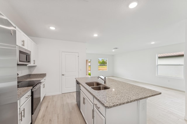 kitchen featuring appliances with stainless steel finishes, a sink, a kitchen island with sink, and white cabinets