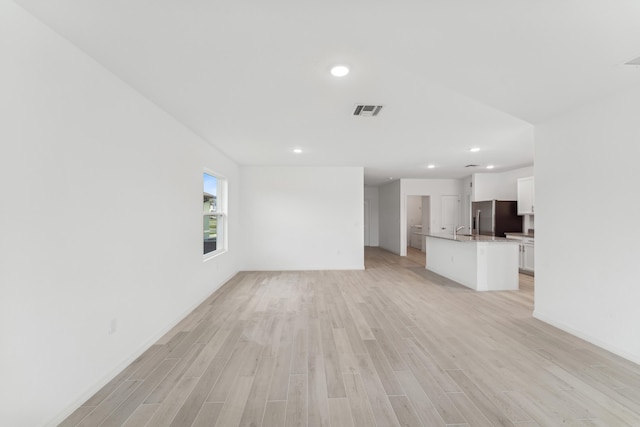 unfurnished living room featuring recessed lighting, a sink, visible vents, baseboards, and light wood-style floors