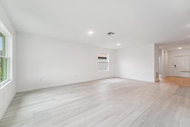 unfurnished room with baseboards, light wood-type flooring, visible vents, and recessed lighting