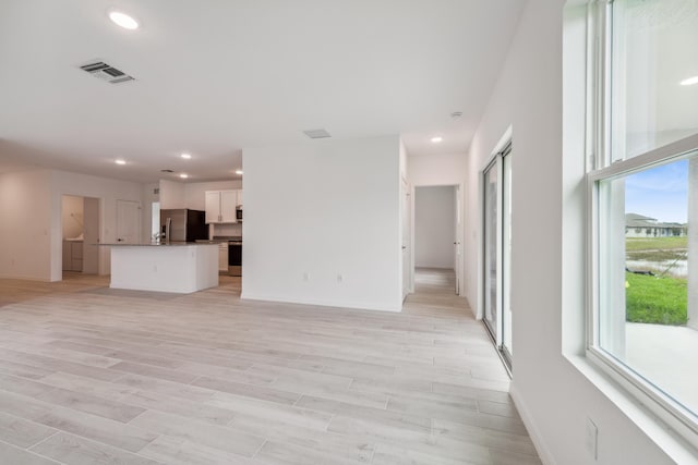 unfurnished living room with recessed lighting, visible vents, light wood-style flooring, and baseboards