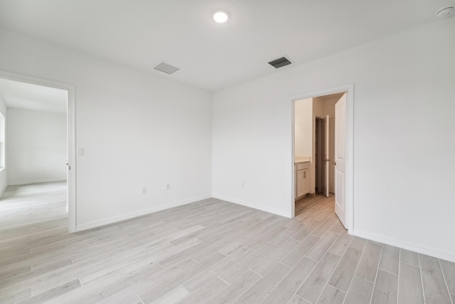 spare room featuring light wood-type flooring, visible vents, and baseboards