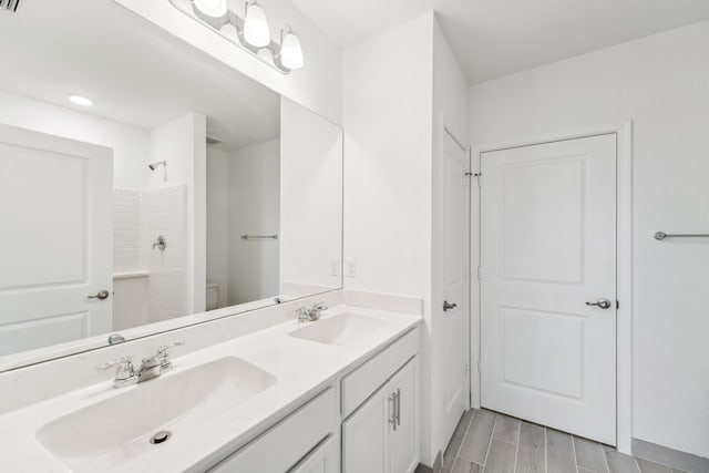 full bath with toilet, double vanity, a shower, and a sink