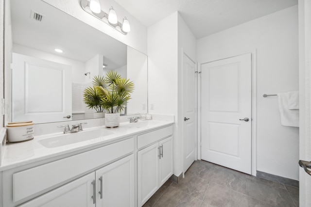 bathroom with double vanity, visible vents, and a sink